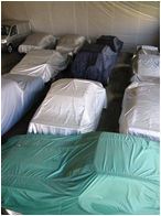 Various classic & new vehicles underneath breathable dust covers inside the car storage warehouse